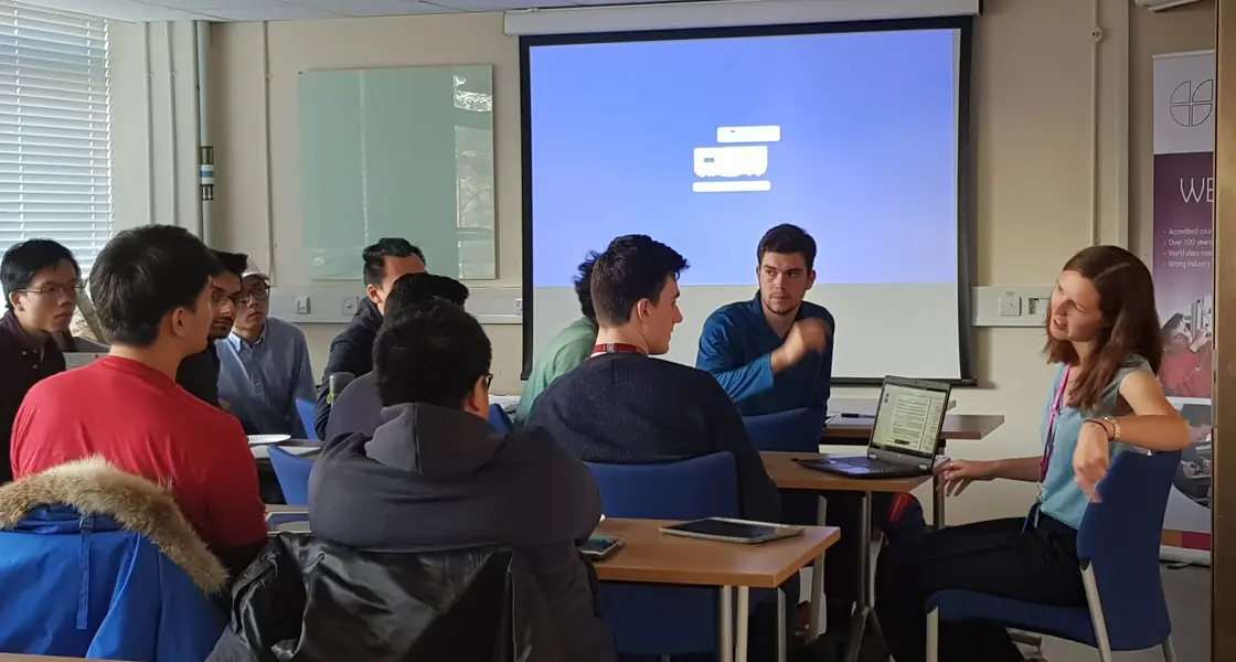 Group of students and teacher sat in classroom discussing